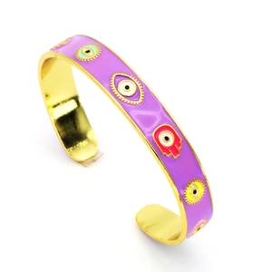 Macro detail of gold-plated bangle with purple enamel and colorful evil eye accents