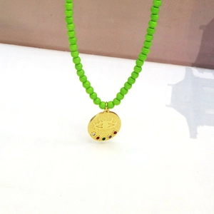 Détail du collier de perles vert vif avec pendentif pièce Mauvais Œil doré et pierres