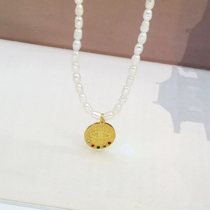 Vue détaillée d'un collier de perles d'eau douce et pendentif œil maléfique doré