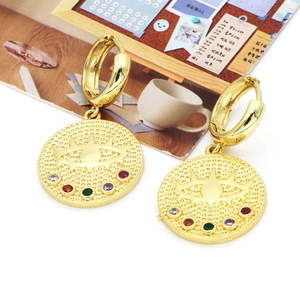 Boucles d'oreilles Evil Eye dorées avec pierres multicolores sur fond de magazine