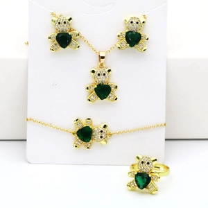Détail de bijoux ours doré avec pierres en forme de cœur vert et zircons blancs étincelants