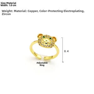 Detail of adjustable golden copper ring with bear head, white zircon and green stone eyes
