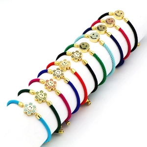 Array of colorful hand-woven bracelets featuring gold-plated smiley face and sun charms