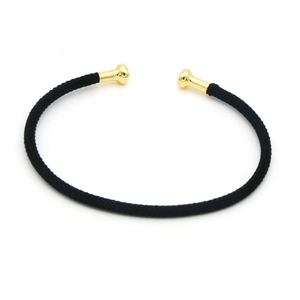 Dettaglio del bracciale a corda intrecciata nera a forma di C con terminali dorati