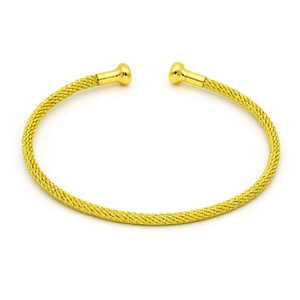 Dettaglio macro del bracciale rigido dorato a forma di C con trama a rete e sfere finali