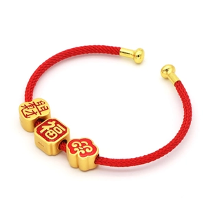 Dettaglio macro del bracciale rosso intrecciato con perle dorate, segno Fu e marchio 999