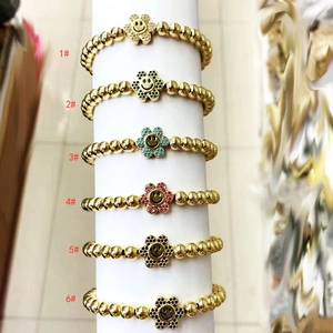 Detail of six bohemian gold bead bracelets with colorful smiley flower charms