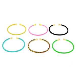 Bracciali intrecciati colorati a forma di C con punte in metallo dorato su sfondo bianco