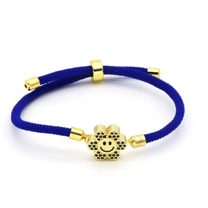 Detail showing hand-woven blue nylon cord and gold flower charm with blue cubic zirconia