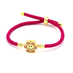 Macro detail of hand-woven rose pink cord bracelet with golden smiley flower charm