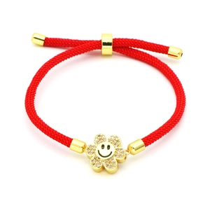 Close-up of red woven bracelet with a golden crystal sunflower and smiley face charm