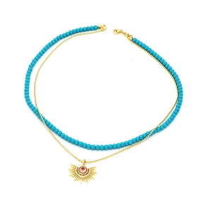 Detail of double-layer necklace with blue beads and sunburst pendant with red crystals