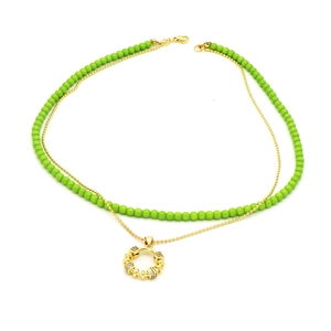 Detail of layered gold chain with green resin beads and a zircon-set hollow ring pendant