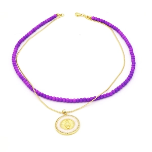 Detail of layered purple bead and gold bead necklace with a religious relief pendant