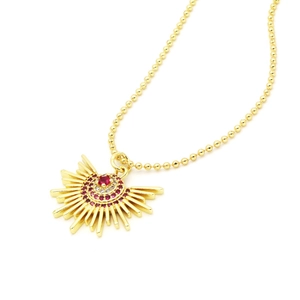 Macro shot of gold sunburst pendant with red and white zircons on beaded chain