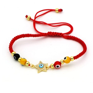 Λεπτομέρεια κόκκινου πλεκτού βραχιολιού Evil Eye με χρυσό αστέρι και πολύχρωμες χάντρες
