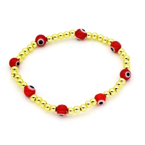 Dettaglio del bracciale con perline rosse malocchio e accenti dorati su sfondo bianco