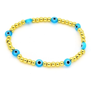 Dettaglio del bracciale con perline dorate e ciondoli blu turchi dell'occhio del male