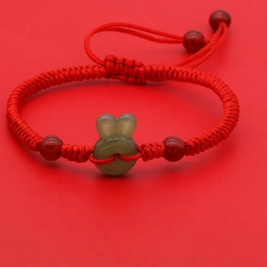 Dettaglio del bracciale rosso intrecciato con coniglio di giada verde e perle d'agata