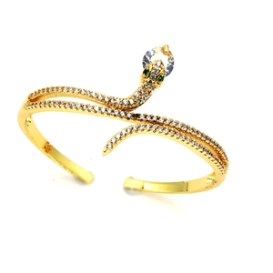 Goldenes Schlangenarmband mit weißem Zirkonia-Besatz und grünen Kristallaugen auf Weiß