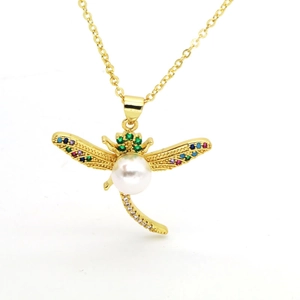 Macro view of gold dragonfly pendant with colorful zircons and a white pearl on wings