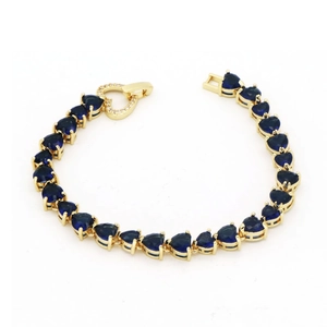 Detail of heart-cut blue zircon tennis bracelet with gold plating and paved heart clasp