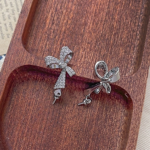 Macro shot of silver bow earring components with micro-set cubic zirconia on wood