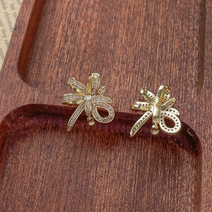 Close-up of gold-plated bow earrings with micro-pave white zircon on a wooden tray