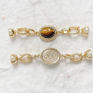 Dettaglio di chiusure per gioielli placcate oro 18k con occhio di tigre e rilievo floreale
