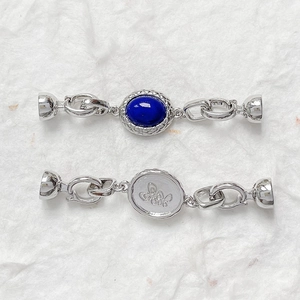 Dettaglio macro di connettori in argento con gemma blu e motivo a farfalla inciso