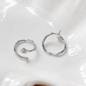 Dettaglio di orecchini in argento a forma di ramo con boccioli di rosa su bianco