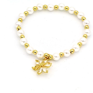 Close-up of pearl beaded bracelet with gold flower charm and sparkling crystals