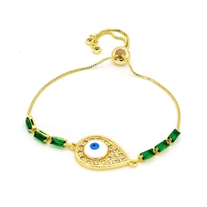 Detail of adjustable golden evil eye bracelet with blue pupil and green zircon stones