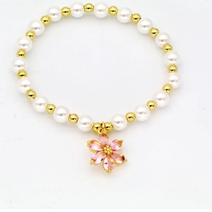 Detail of beaded bracelet with white pearls, gold beads and a pink flower pendant