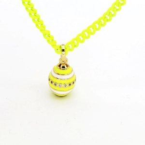 Close-up of a neon yellow egg pendant necklace with white stripes and cubic zirconia stones