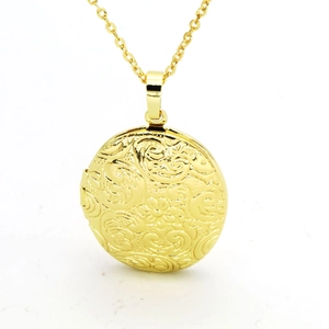 Detailed close-up of a gold oval locket necklace with vintage floral engraving detail