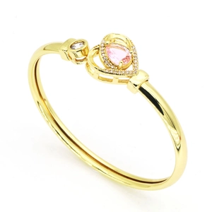Détail du bracelet doré ouvert avec une pierre rose en forme de poire et cœur.