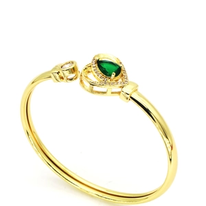 Vue détaillée d'un bracelet jonc doré orné d'une pierre précieuse verte en forme de cœur