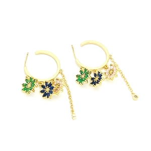 Detalle macro de pendientes de aro dorados con colgantes de flores de circonita