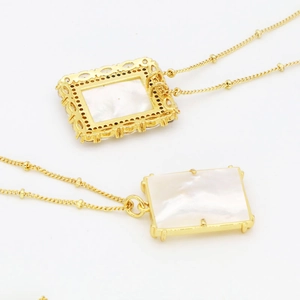 Vue macro du collier Maria avec nacre blanche et sculpture creuse dorée élégante