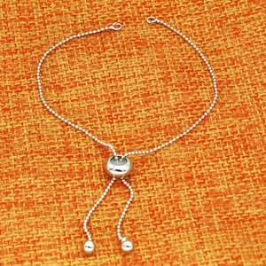 Détail d'un bracelet à perles argentées ajustable avec fermoir coulissant doré 18 carats
