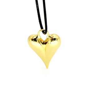 Detalle de colgante de corazón dorado pulido 3D con cordón negro sobre fondo blanco