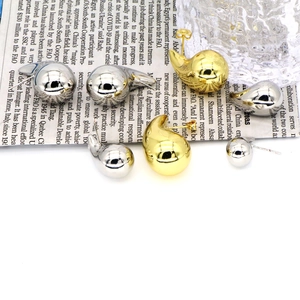 Detailed view of polished gold and silver waterdrop earrings on a decorative paper background