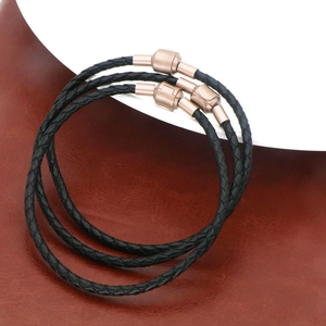 Gros plan de bracelets en cuir tressé noir avec fermoirs magnétiques en or rose