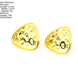 Detalle macro de pendientes geométricos dorados con una superficie texturizada