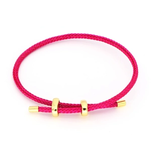 Nahaufnahme von rosarotem geflochtenem Seilarmband mit polierten goldfarbenen Schiebeperlen