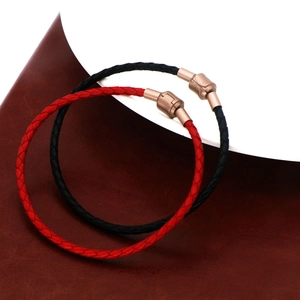 Détail de bracelets en cuir tressé rouge et noir avec des fermoirs magnétiques en métal
