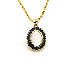 Macro detail of gold oval pendant featuring Mother Mary relief and blue cubic zirconia stones