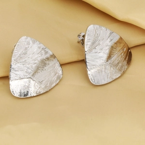 Vista macro de pendientes geométricos plateados con textura cepillada radial detallada