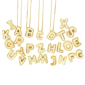 Makroansicht goldener Buchstabenanhänger mit Zirkonia-Mikropavé an feinen Goldketten
